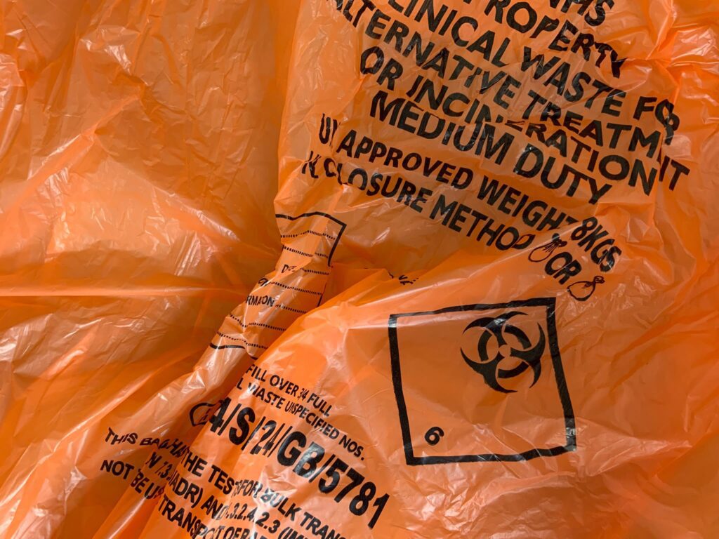 Closeup shot of the biohazard symbol on an orange waste bag for biohazard removal for FAQs